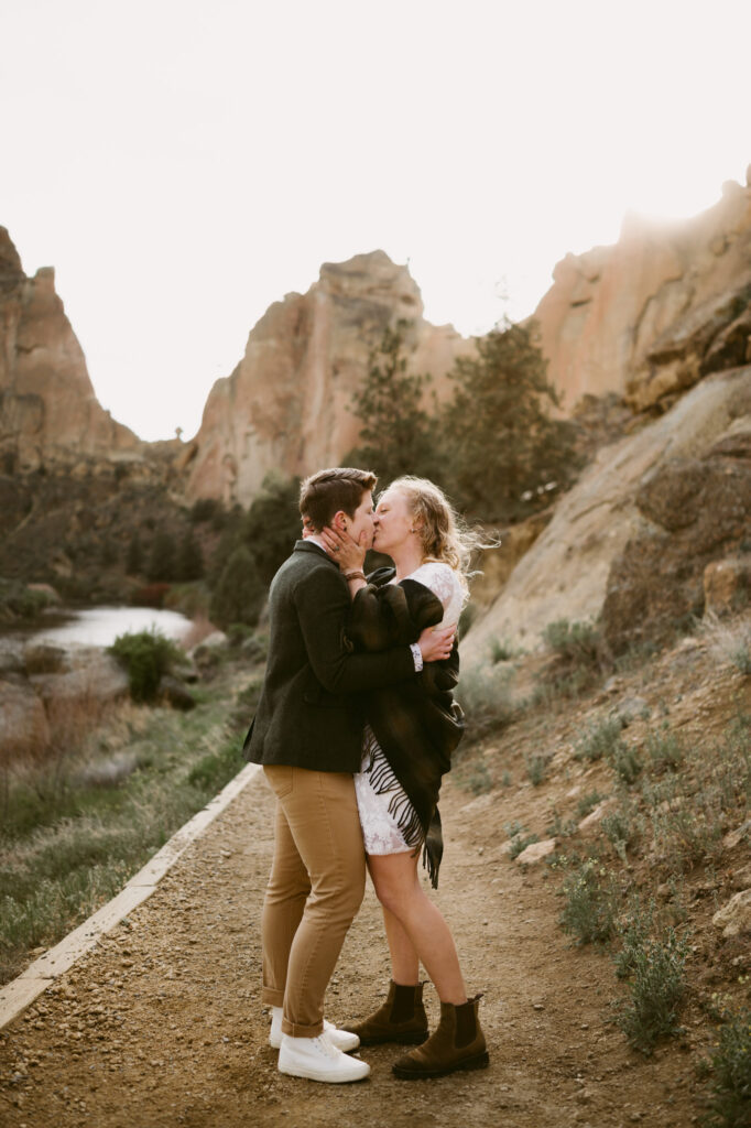 Two women face each other and kiss on a dirt path at Smith Rock State Park in Terrebonne, Oregon.