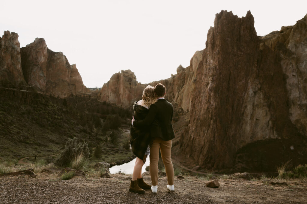 Two women stand close together at an overlook at Smith Rock State Park.