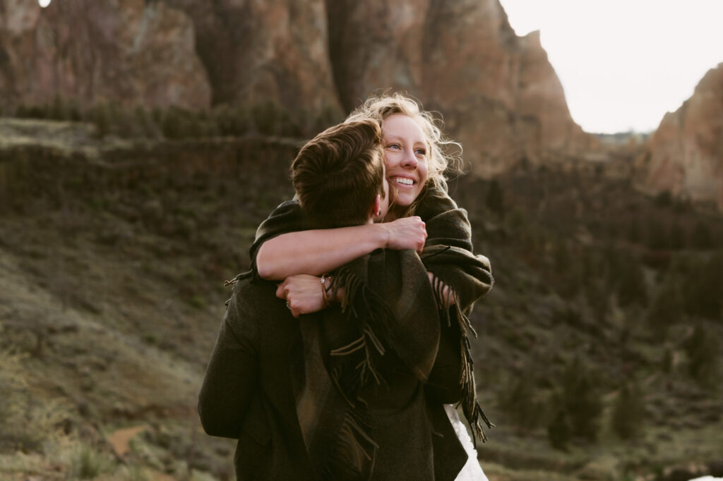 Two women embrace at Smith Rock State Park. We only see the face of the first woman as the second woman has her back to the camera.