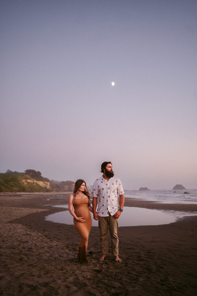 A young couple pose at twilight on Seal Rock Beach during their engagement session in Seal Rock, Oregon.