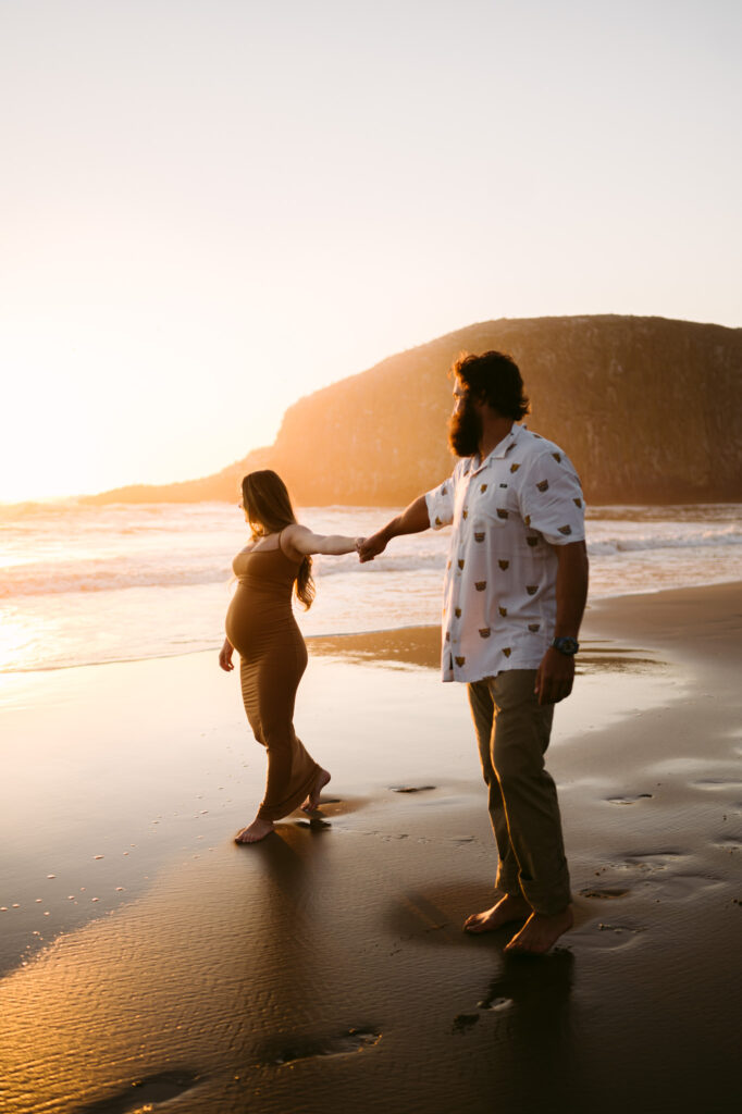 A pregnant woman and man take maternity photos at sunset at Seal Rock Recreation Site in Seal Rock, Oregon.