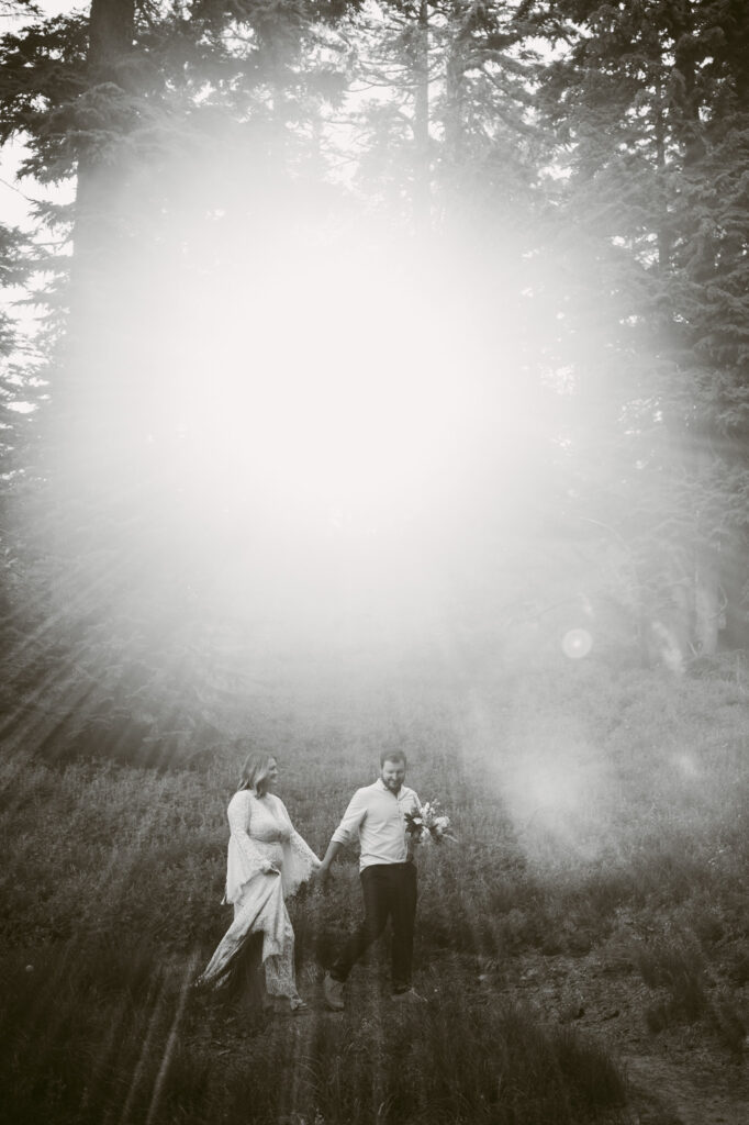 A black and white image of a groom leading his bride down a hiking trail at Mount Hood Meadows Ski Resort.