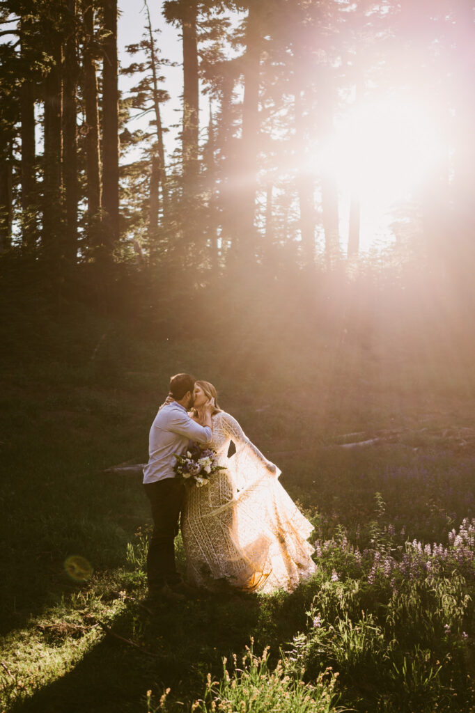 A bride and groom stand in a ray of sun on Mount Hood during their Mount Hood Meadows wedding.
