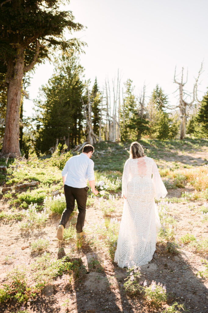 A bride and groom walk away from the camera during their late summer elopement at Mount Hood Meadows