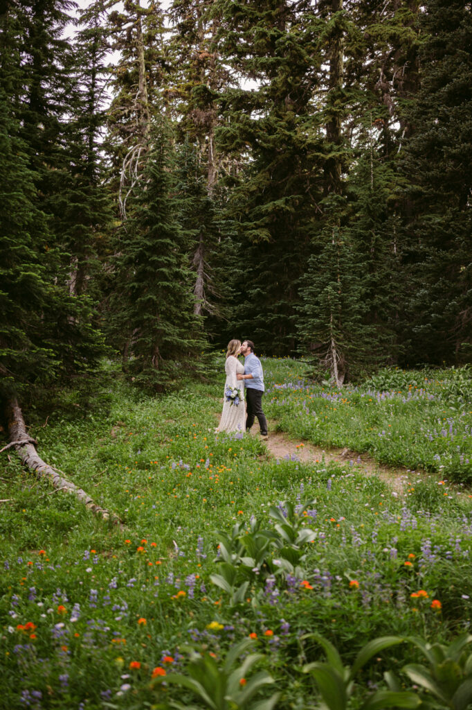 A groom pauses to kiss his bride on a hiking trail during their Mount Hood elopement.