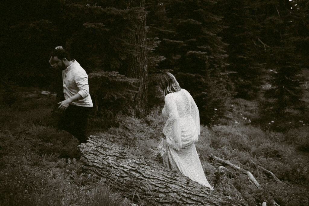 A black and white image of a bride and groom hiking through the woods on Mount Hood.