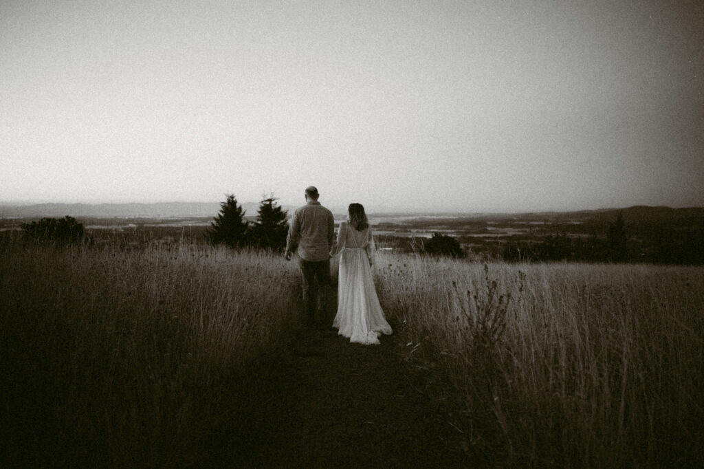 A black and white photo of a married couple walking hand-in-hand along a footpath at Fitton Green in Corvallis, Oregon.