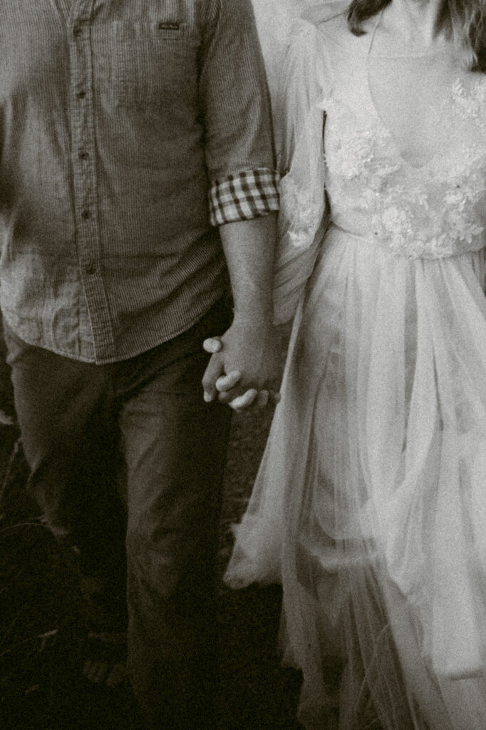 A close-up black and white image of a man and woman holding hands.