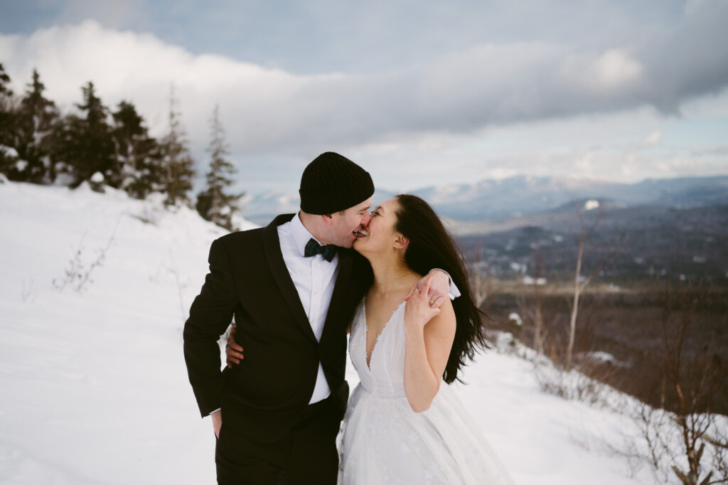A recently married couple smile and kiss during their Adirondack elopement.