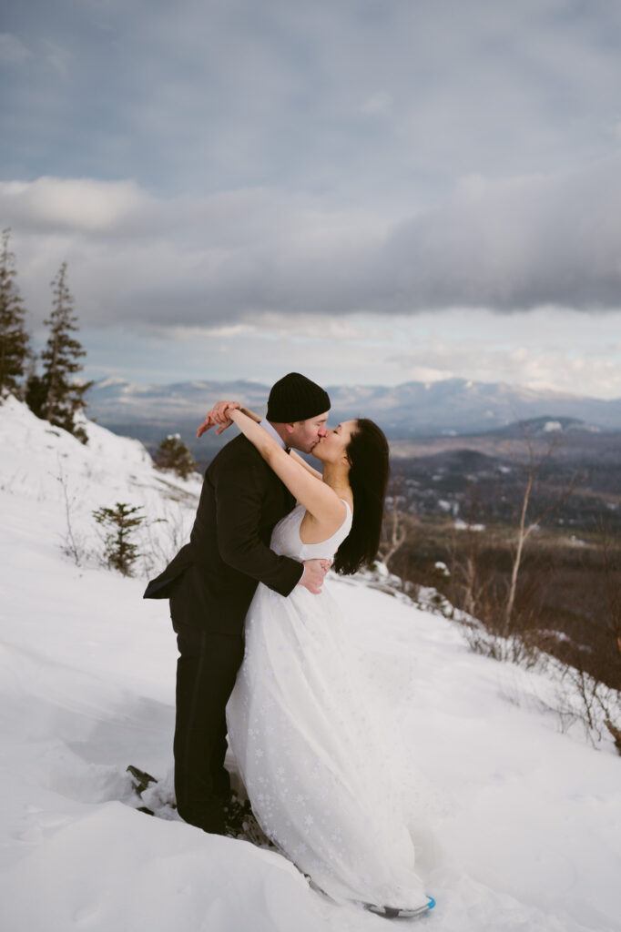 A married couple kisses at Cobble Lookout during their winter Adirondack elopement.