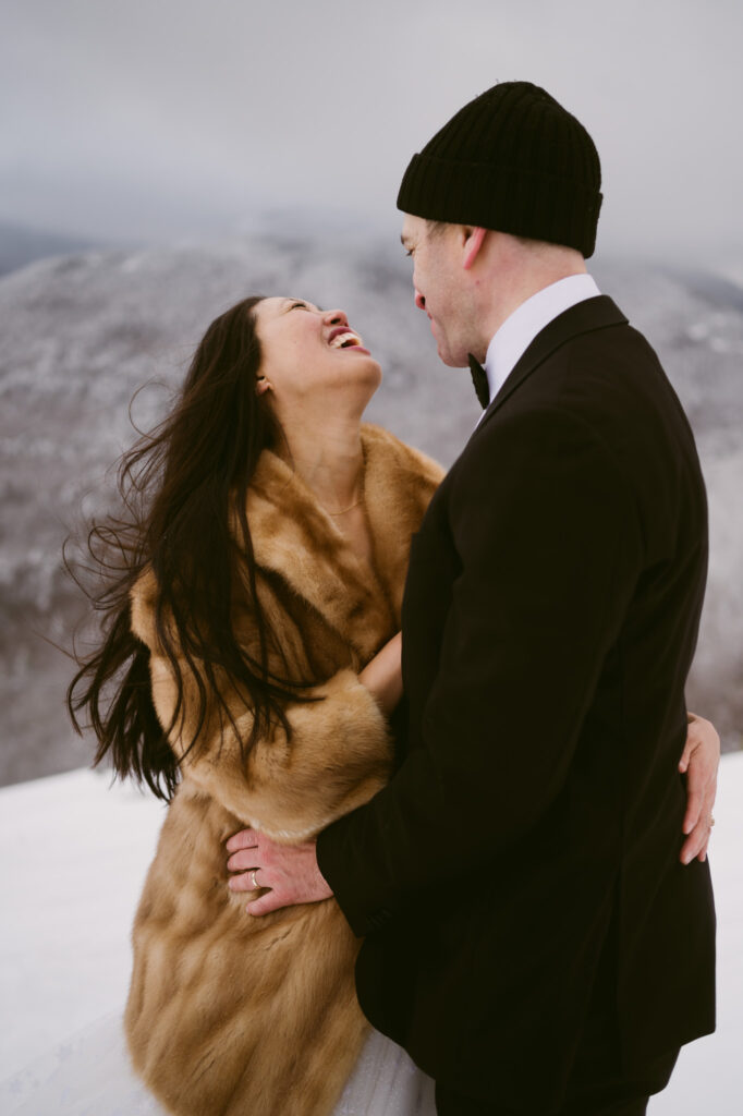 A bride and groom stand in a snowy mountain landscape during their winter Adirondack elopement in Lake Placid, NY.