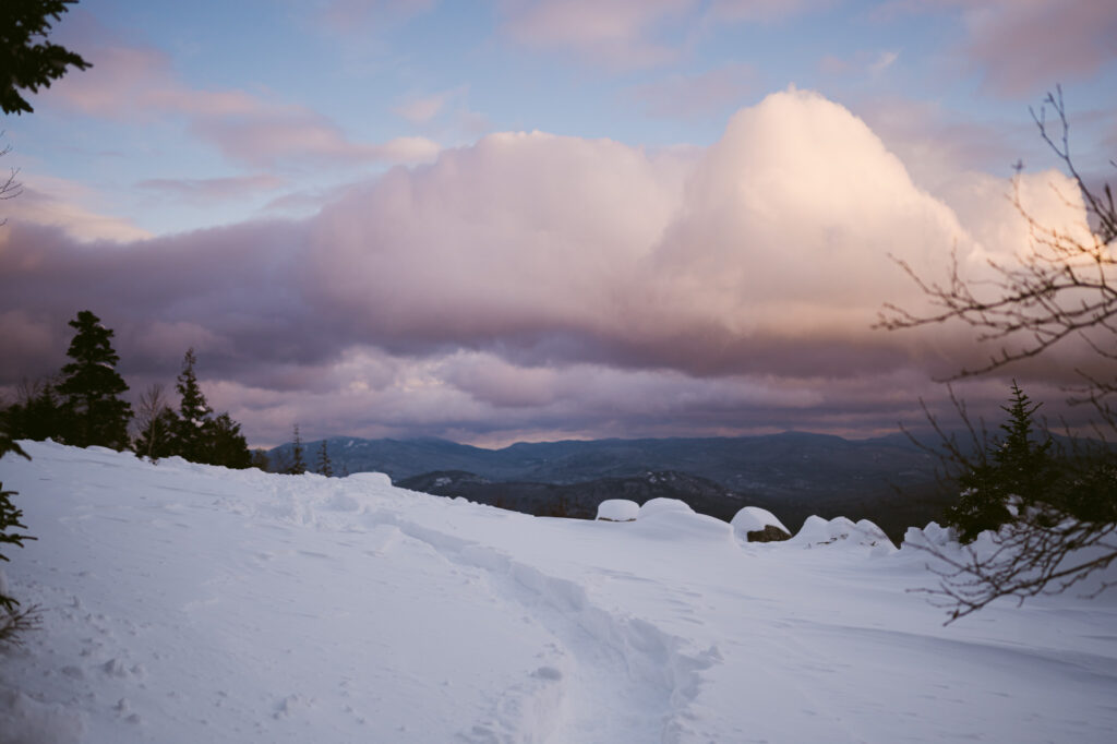 Cotton candy clouds float across a winter scene at Cobble Lookout in Wilmington, New York.