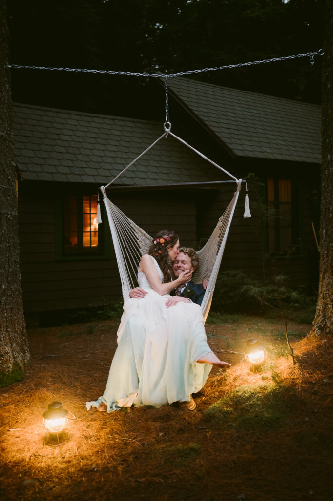 Celebrating their Saranac lake wedding, a bride and groom cozy up together on a hammock chair.